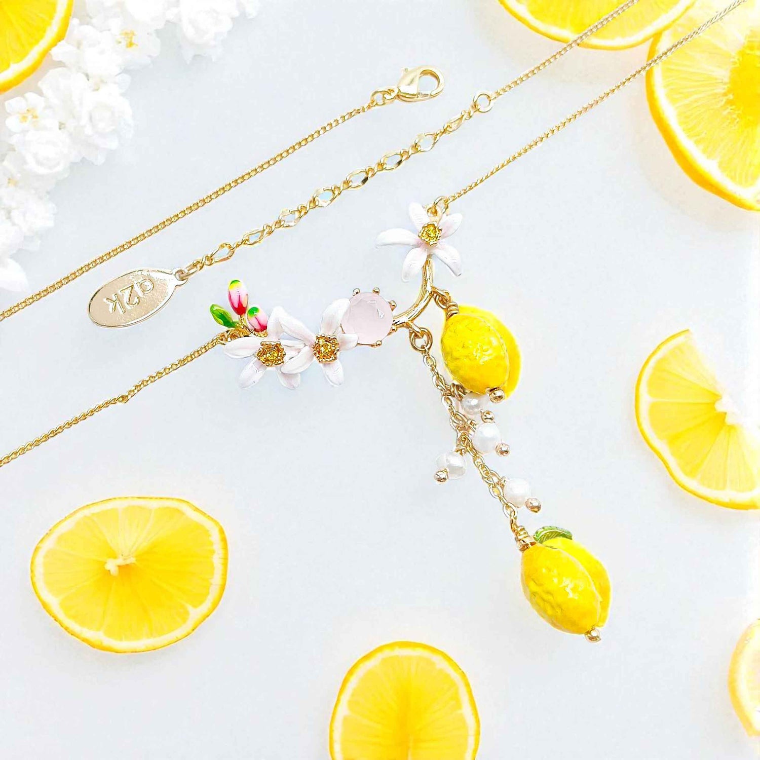 Necklace with lemon-shaped pendants on a white background with lemon slices