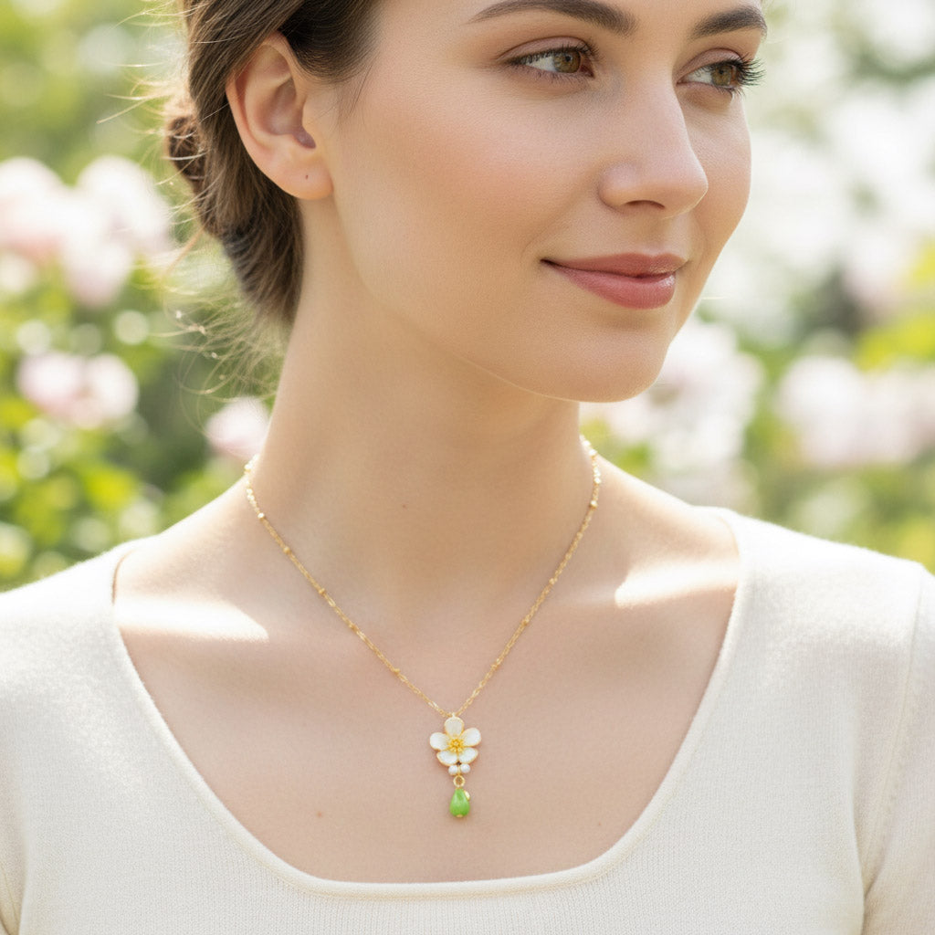 Woman wearing a delicate necklace with a floral pendant in an outdoor setting