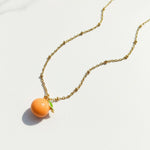 Necklace with orange-shaped pendant on a white background
