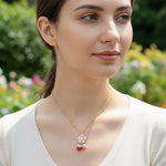 Woman wearing a gold necklace with a floral pendant in a garden setting