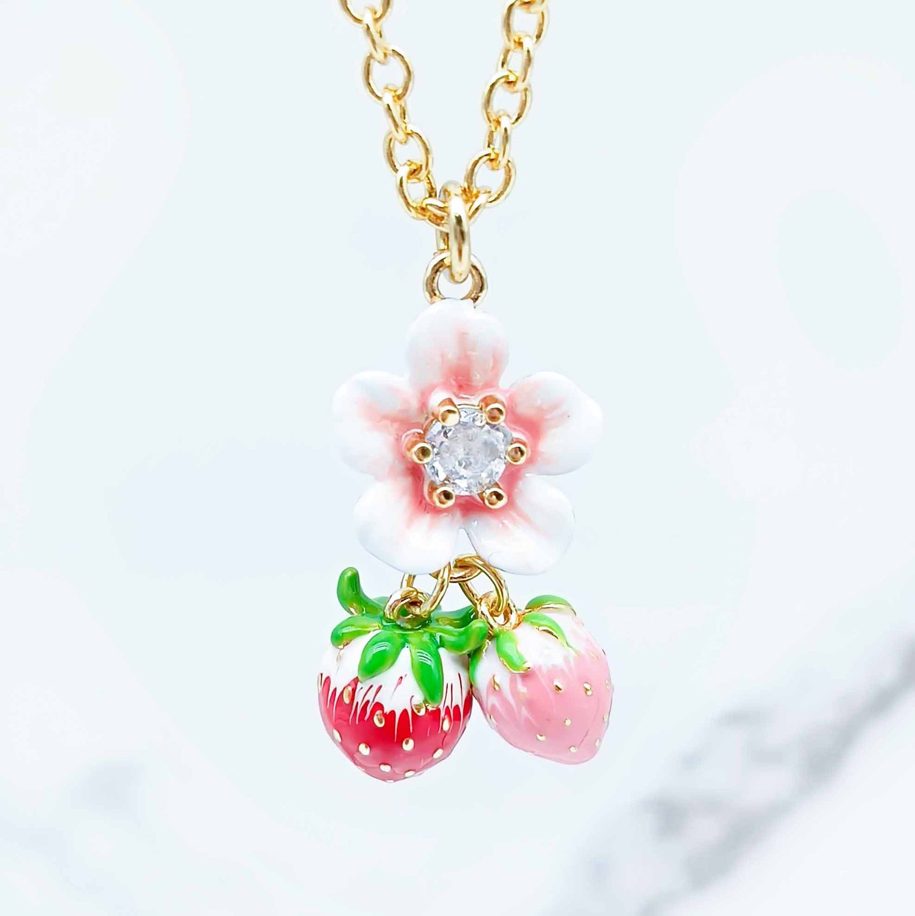 Necklace with strawberry and flower pendant on a light background