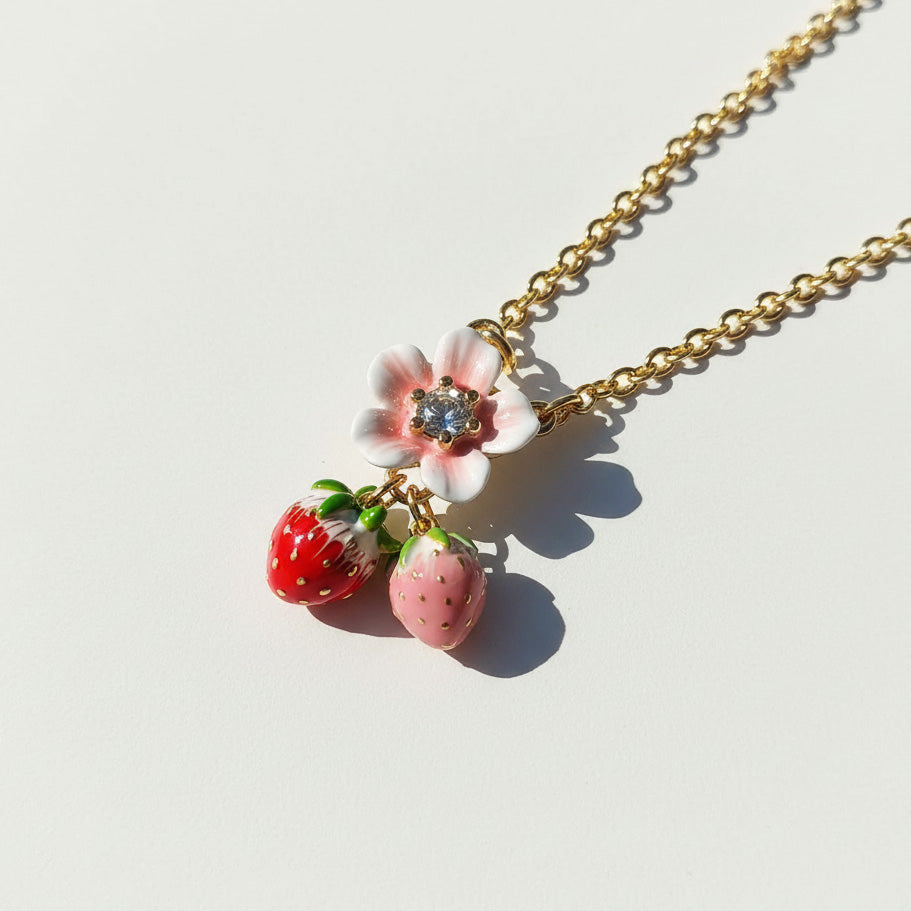 Necklace with strawberry and flower charms on a light background
