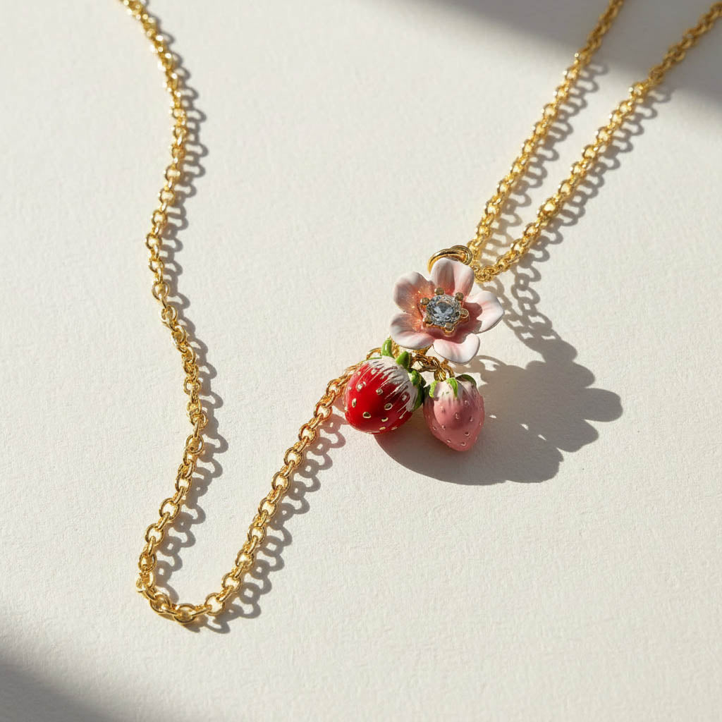 Necklace with strawberry and flower pendant on a light background