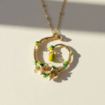 Close-up of gold enamel pear blossom pendant with hanging pear charm