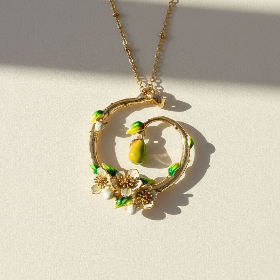Close-up of gold enamel pear blossom pendant with hanging pear charm