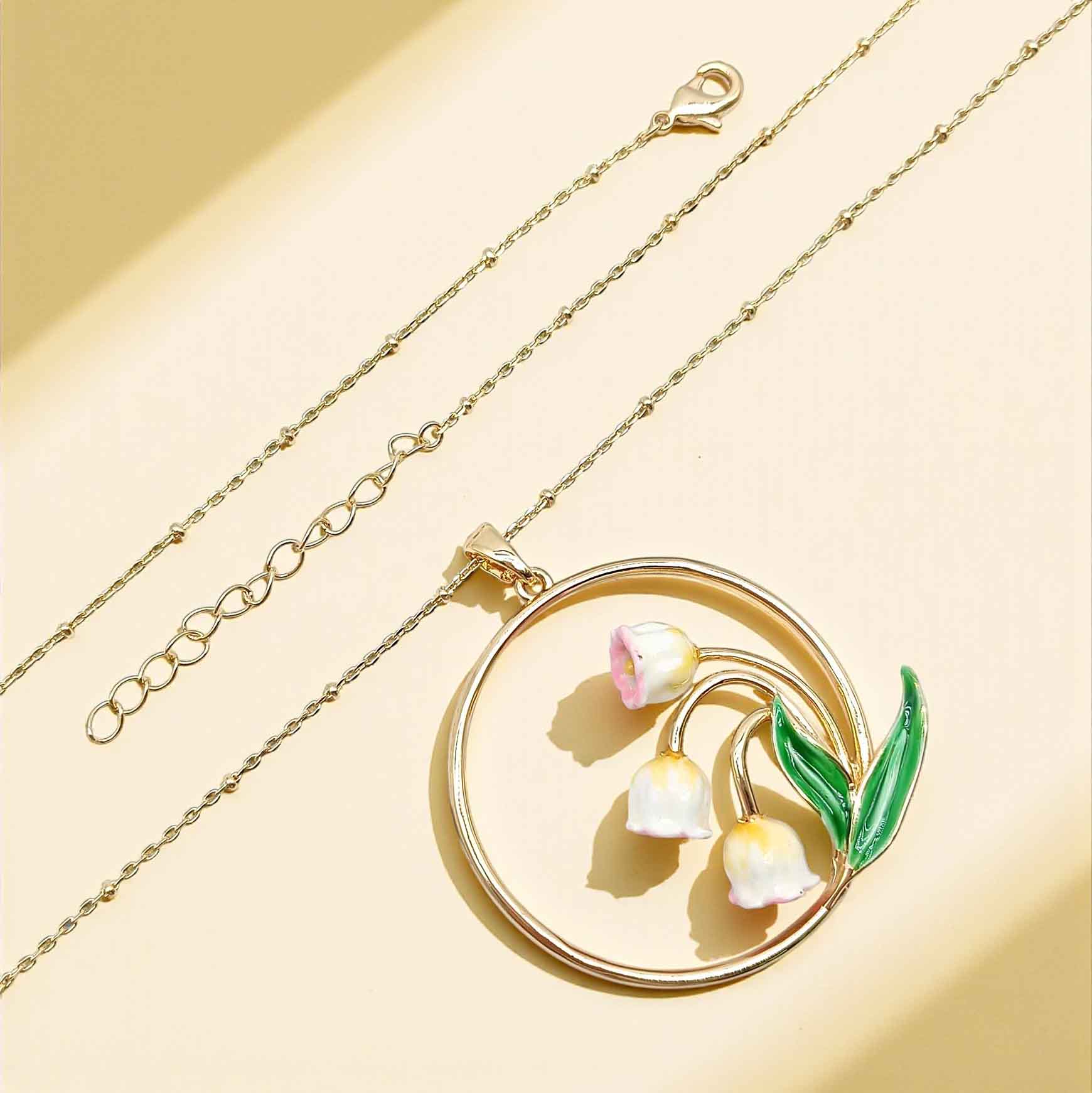Gold necklace with a floral pendant on a beige background