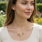 Woman wearing a gold necklace with floral pendants outdoors