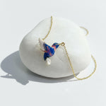 Hummingbird necklace on a white stone surface