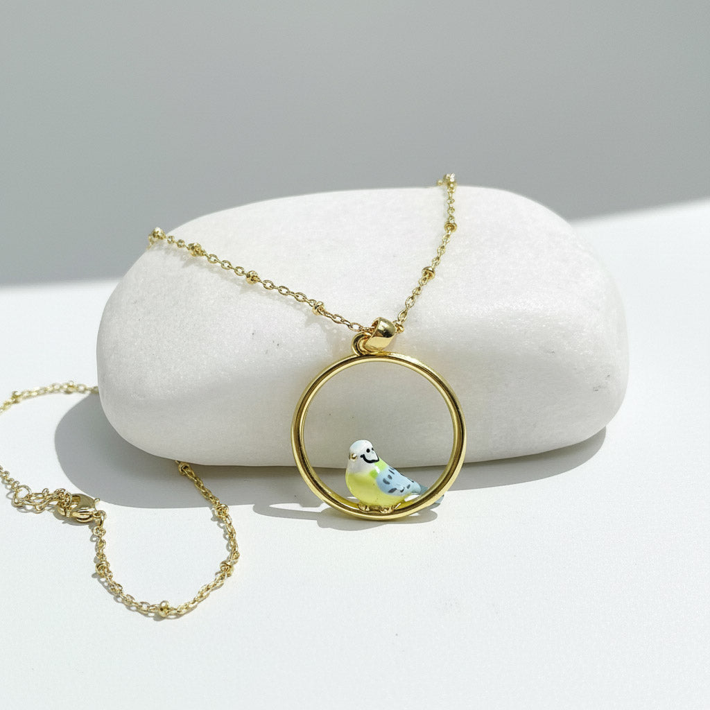 Gold necklace with a bird pendant on a white stone surface