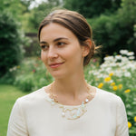 Woman wearing a gold necklace with a floral design outdoors