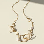 Gold necklace with butterfly and pearl details on a beige background