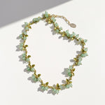 Botanical berry necklace featuring mint green stone clusters and olive green enamel leaves, gold-tone finish