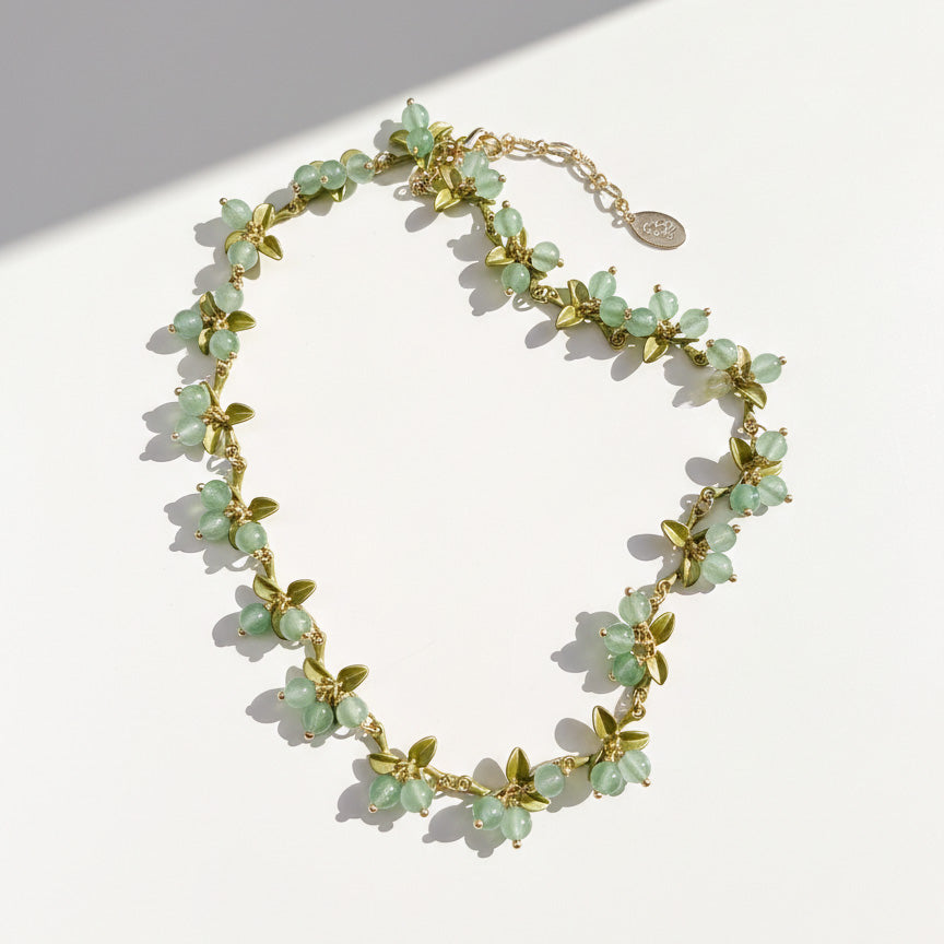 Botanical berry necklace featuring mint green stone clusters and olive green enamel leaves, gold-tone finish