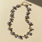 Necklace with purple floral beads on a beige background
