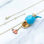 Necklace with a blue whale pendant and gold chain on a white background