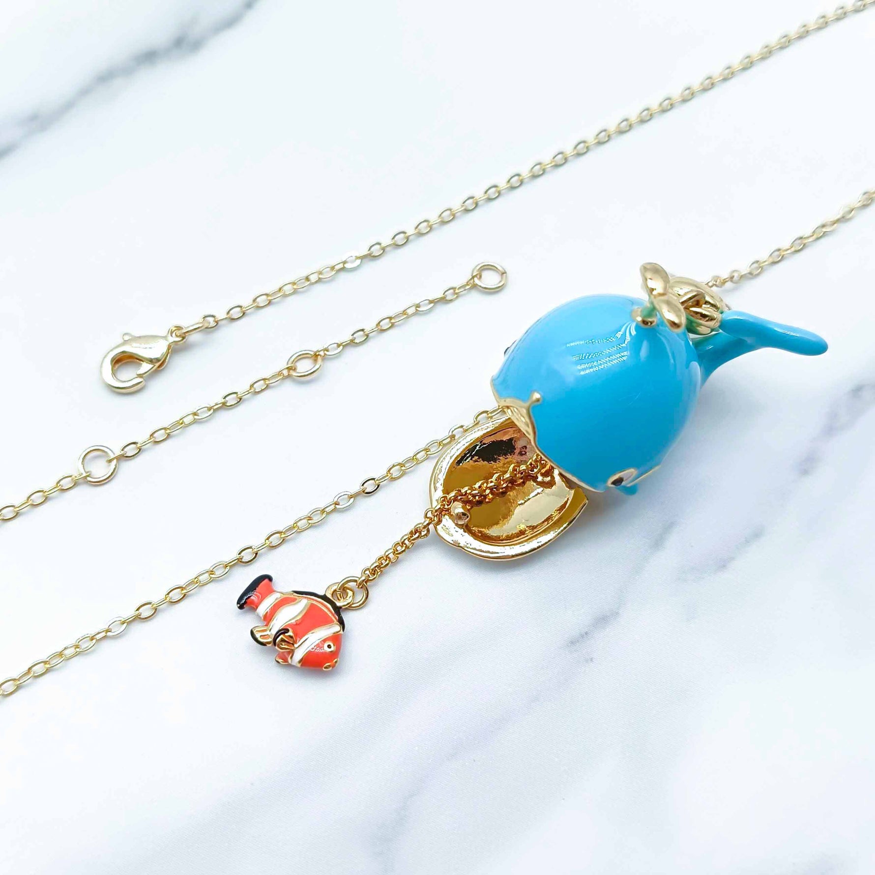 Necklace with a blue whale pendant and gold chain on a white background