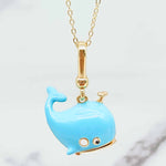 Blue whale-shaped pendant on a gold chain against a light background