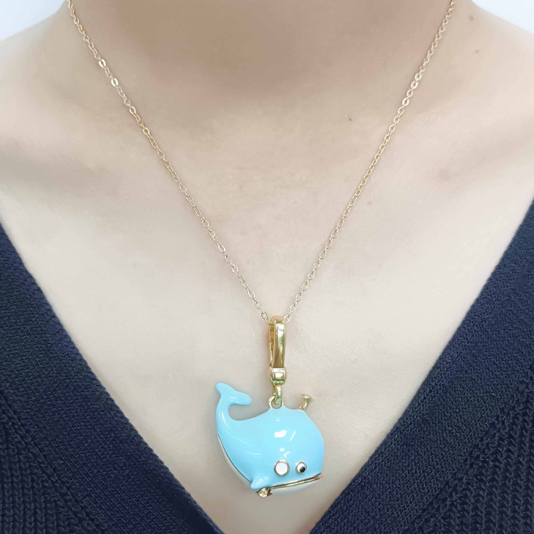 Necklace with a blue whale pendant on a mannequin wearing a navy sweater.