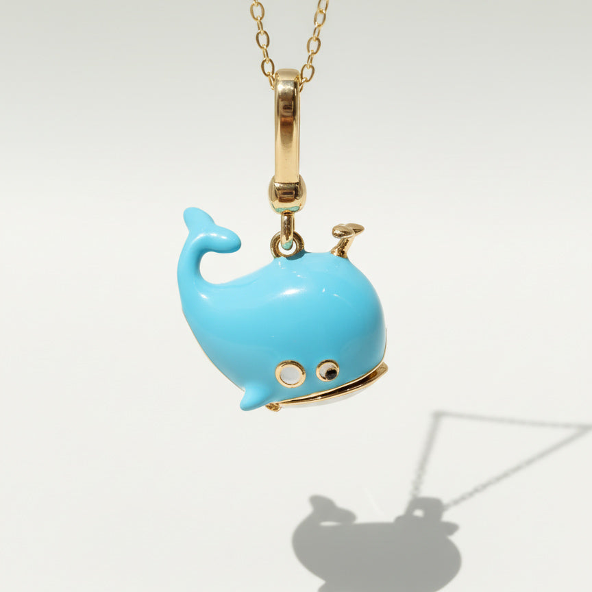 Blue whale-shaped pendant on a gold chain against a white background