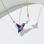 Colorful bird-shaped pendant on a gold chain against a white background