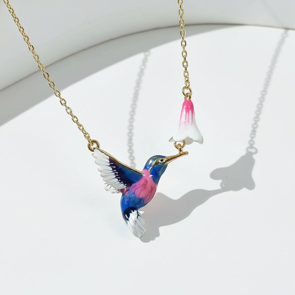 Colorful bird-shaped pendant on a gold chain against a white background