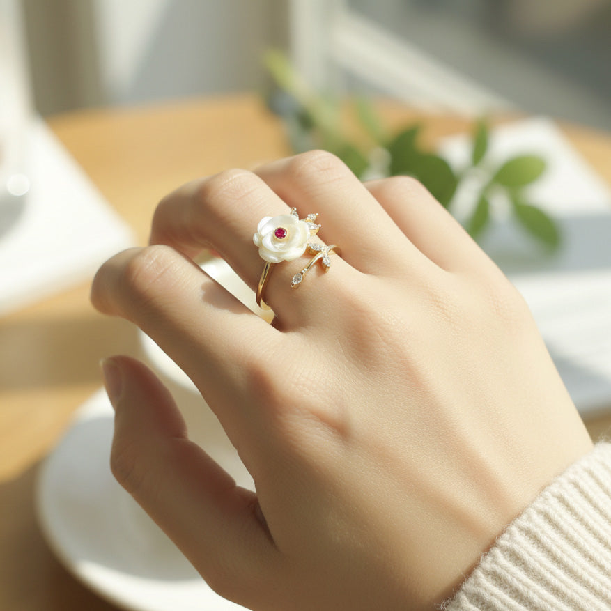 Hand wearing a decorative ring with a flower design on a blurred background