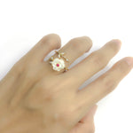 Elegant adjustable gold-plated birthstone ring with white mother-of-pearl flower and pink stone accent, worn on a hand.