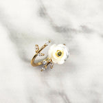 Delicate gold-plated adjustable ring featuring a mother-of-pearl flower with a birthstone center and sparkling cubic zirconia accents, resting on marble