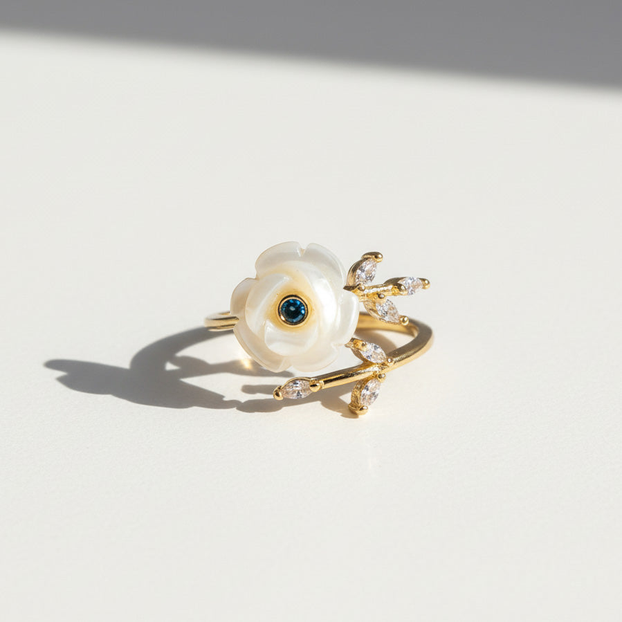 Gold ring with a pearl and gemstone on a light background