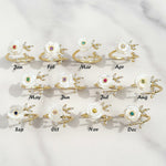 Set of twelve floral earrings with colored gemstones, each labeled for a month on a light gray background.