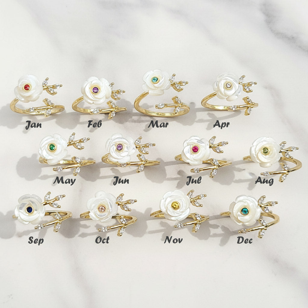 Set of twelve floral earrings with colored gemstones, each labeled for a month on a light gray background.