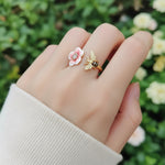Ring with a flower and bee design on a hand against a blurred natural background