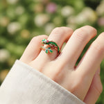 Hand wearing a colorful lizard-shaped ring with a blurred green background