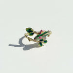 Decorative ring with green and pink accents on a light gray background