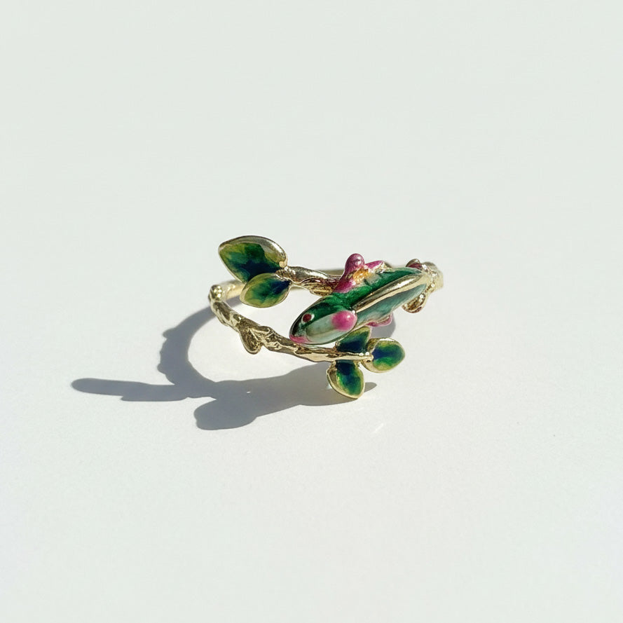 Decorative ring with green and pink accents on a light gray background