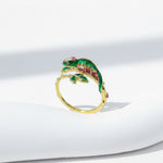 Gold ring with a green lizard design on a white background