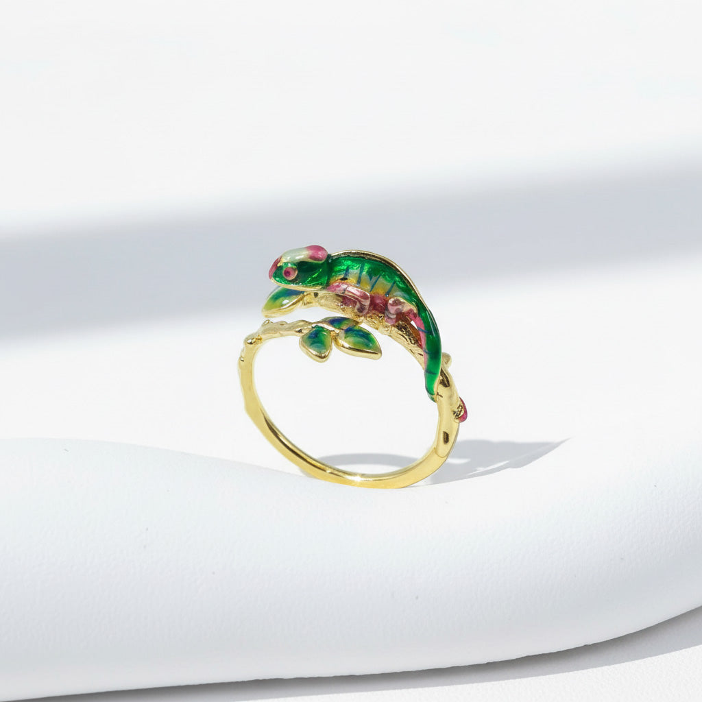 Gold ring with a green lizard design on a white background
