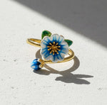 Gold ring with a blue and white floral design on a light surface