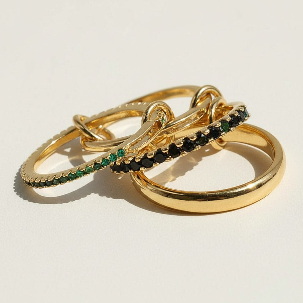 Gold linked ring set with green cubic zirconia stones, featuring four interlocking bands.