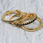 A set of four linked gold-plated rings featuring rich emerald-colored cubic zirconia stones. The rings have a polished and pavé finish, connected by delicate links for versatile styling and an adjustable fit.
