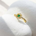 Gold ring with a green gemstone on a white stone surface