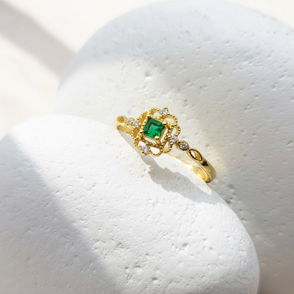 Gold ring with a green gemstone on a white stone surface