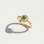 Gold ring with a green gemstone on a light gray background