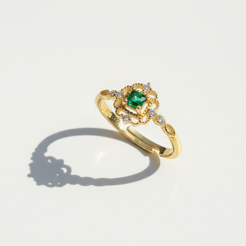 Gold ring with a green gemstone on a light gray background