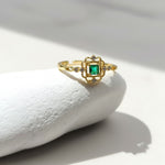 Gold ring with a green gemstone on a white stone surface
