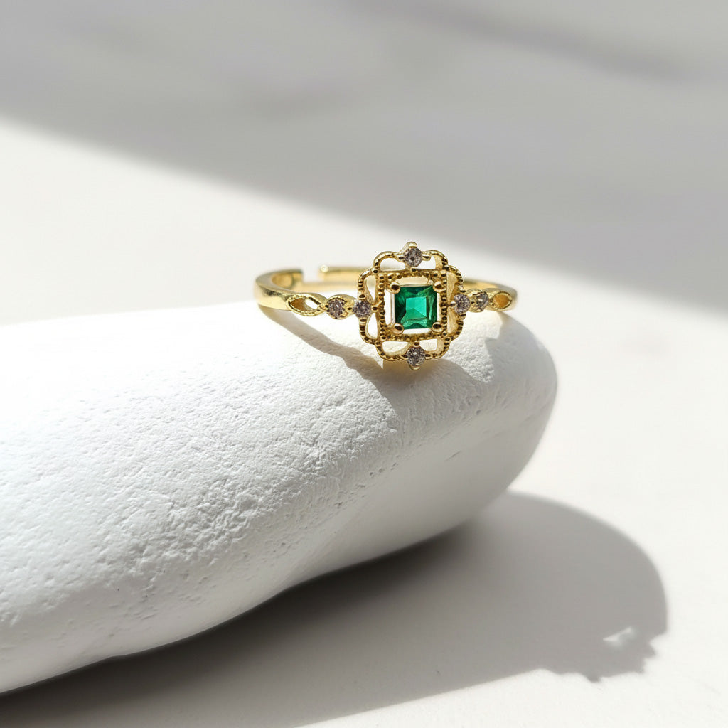 Gold ring with a green gemstone on a white stone surface