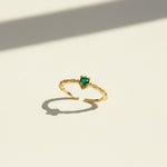 Gold ring with a green gemstone on a light beige background