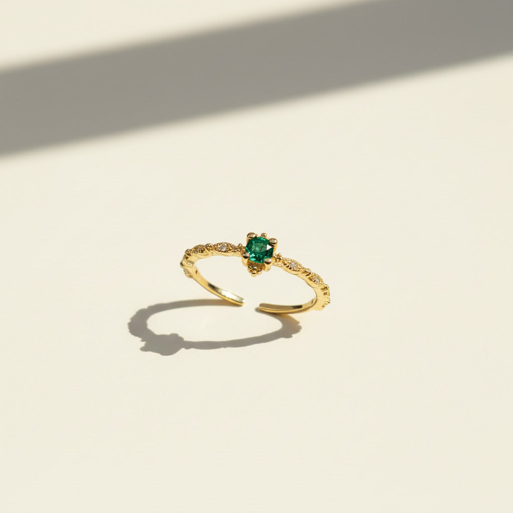 Gold ring with a green gemstone on a light beige background