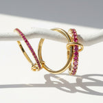 Set of gold linked rings featuring pink cubic zirconia stones, photographed under natural sunlight.