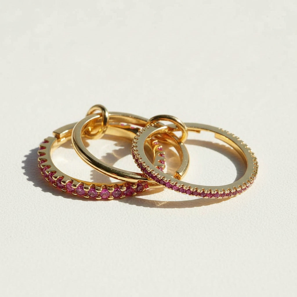 Gold linked ring set with pink cubic zirconia stones, featuring three interlocking bands in sunlight
